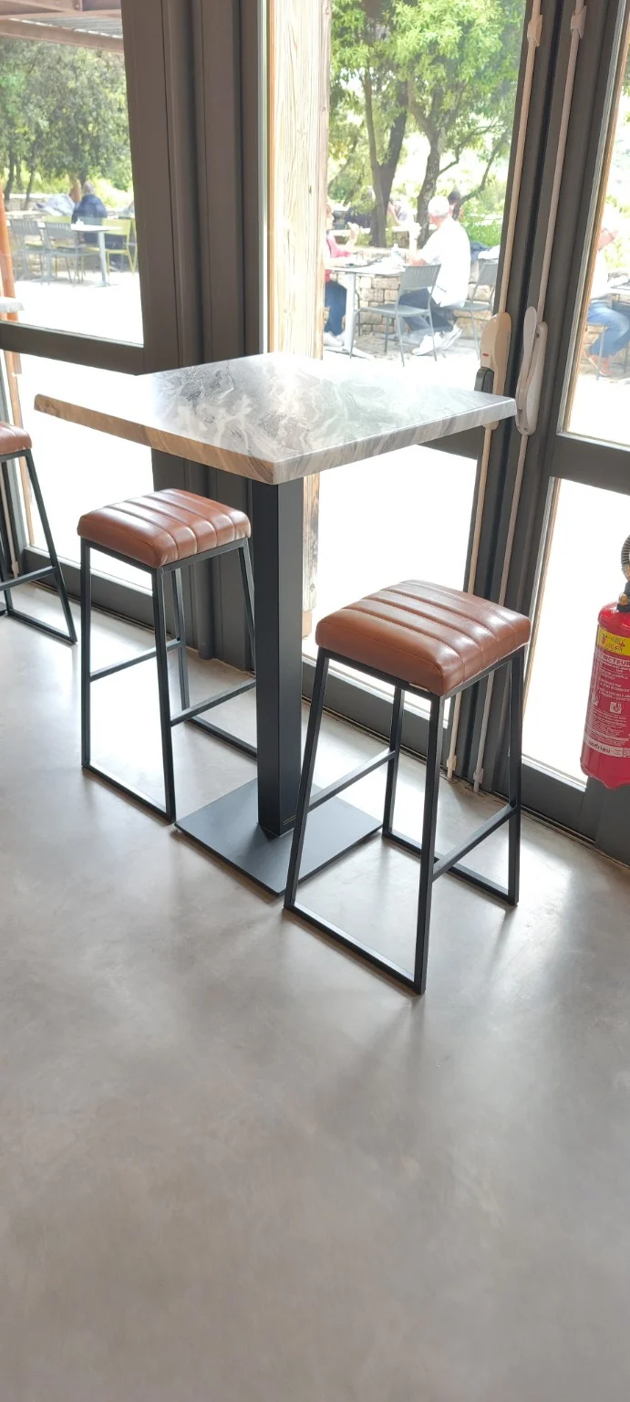 Deux tabourets cognac sans dossier autour d'une table haute